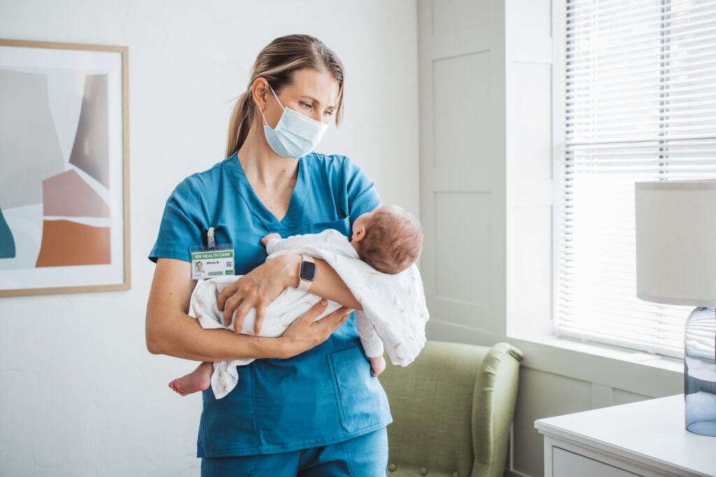 Pediatrician nurse taking care of newborn baby at hospital ward.